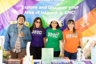 four people in colorful shirts at an outdoor event table
