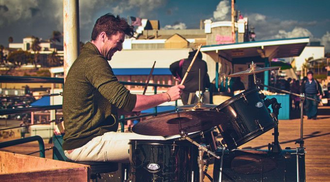 man playing drums on a pier