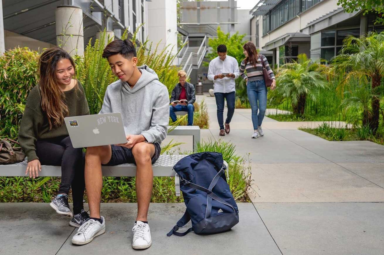 two young people sit on a bench in a beautiful atrium
