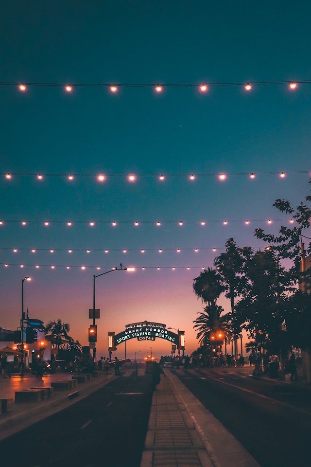 string lights over street and pier entrance at dusk
