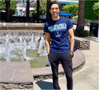 a smiling young man beside a fountain